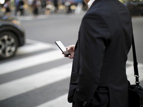 A pedestrian looks at a smartphone as he stands on a corner in Toronto's financial district.