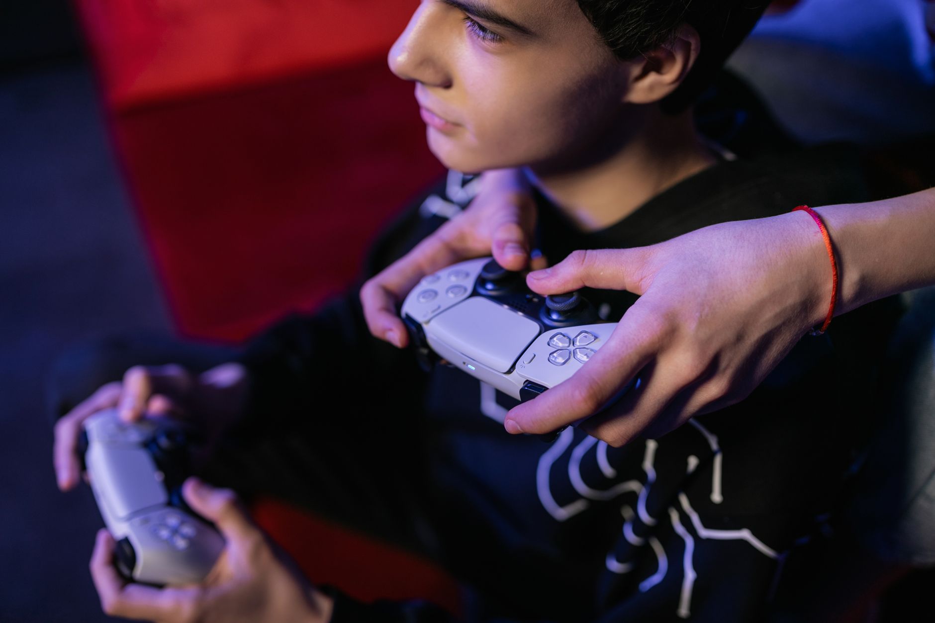 Close-up of teenagers playing video games together using modern game controllers. — Comparing TAG and PSA: Which Grading Serv