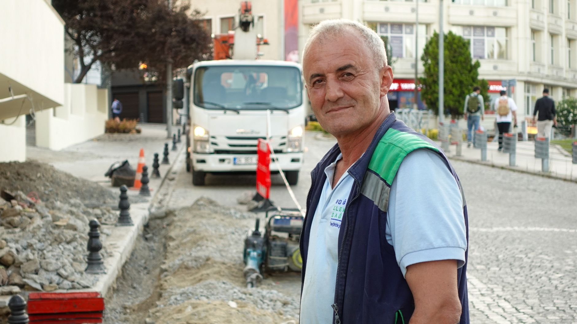 Smiling construction worker on a city street with vehicles and buildings. — Dr Kevin Ciresi: Leadership in Ambulatory Surgery