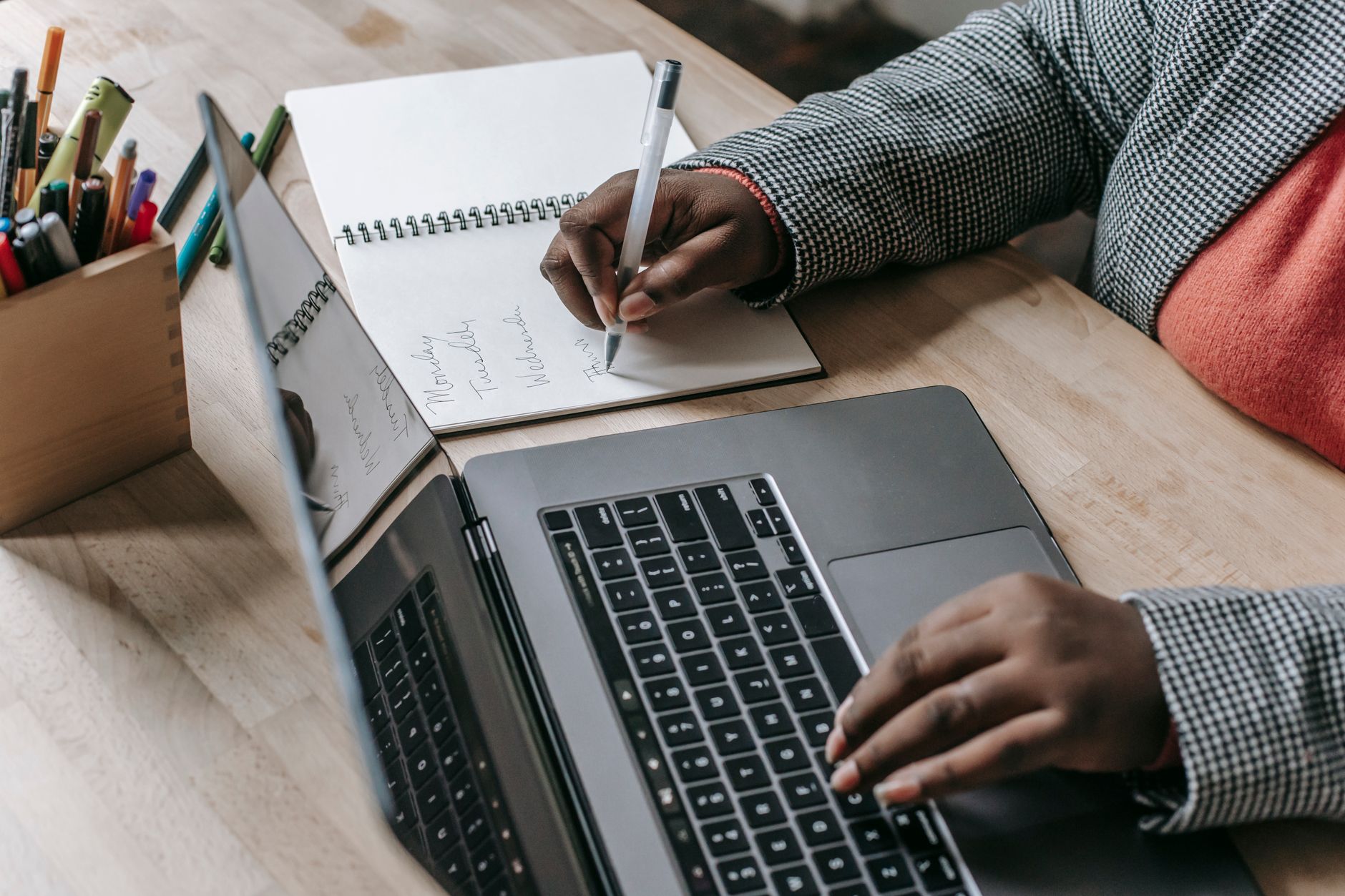 Crop unrecognizable African American female in formal wear writing notes in notepad while working on laptop — Dream Coast Aut