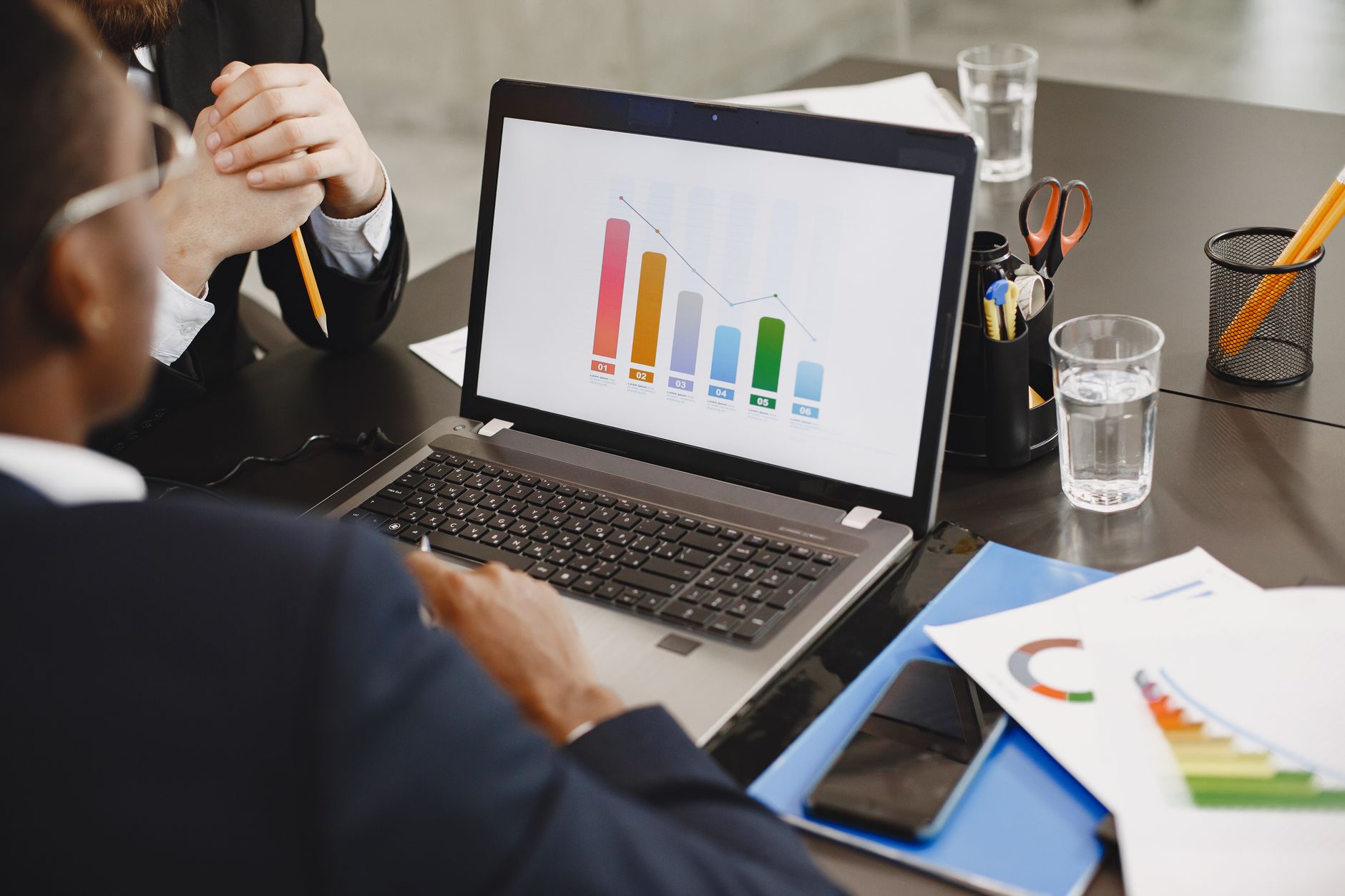 Two professionals analyzing a business graph on a laptop during a meeting. — E Transfer Loans for Fast and Direct Access to F