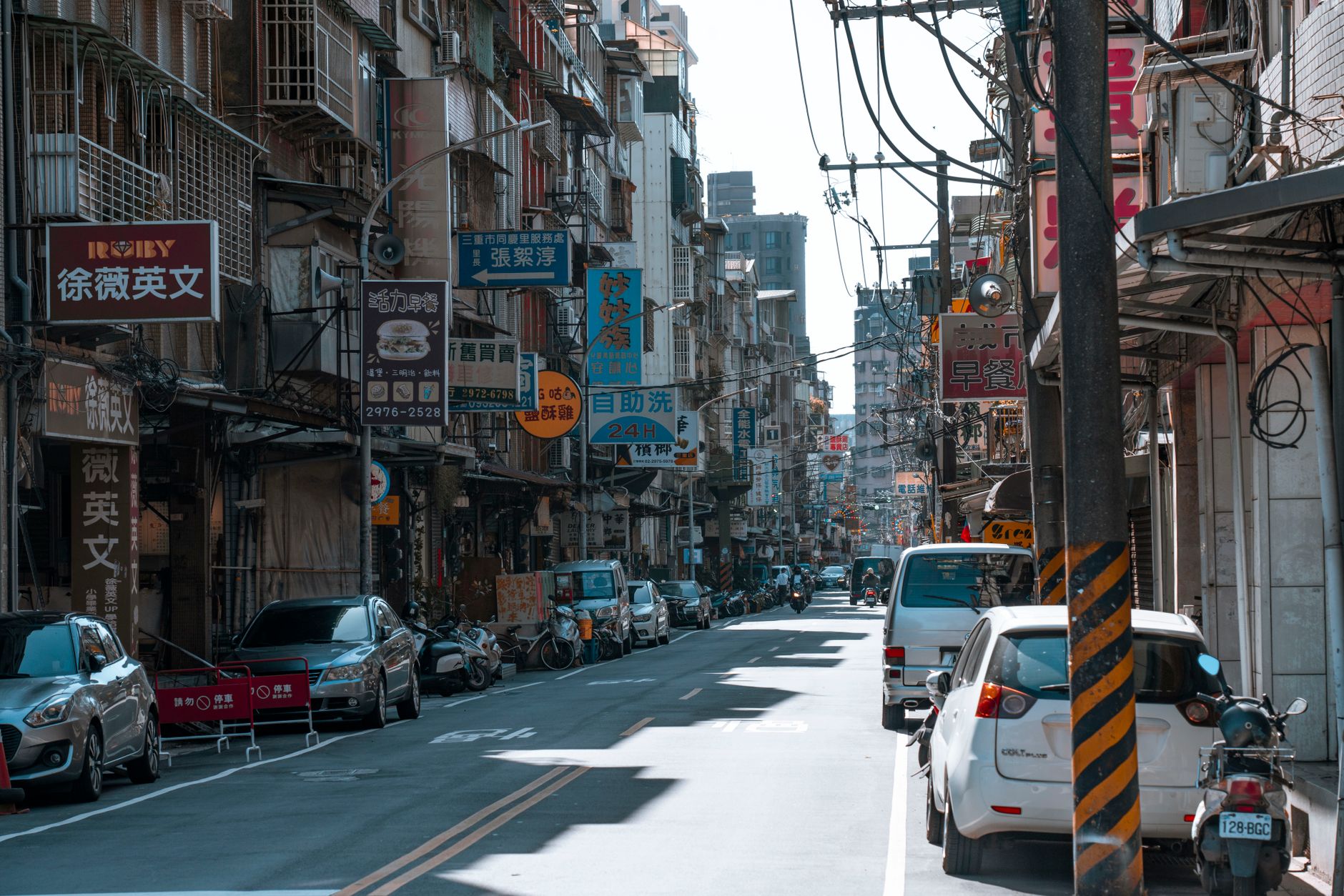 A busy street lined with cars and various colorful business signs on a sunny day. — MedicarePlansGuide.org: Your One-Stop Sho