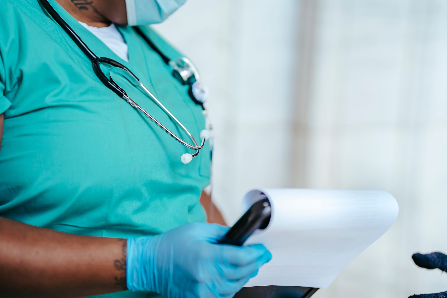 Side view of crop anonymous tattooed ethnic female medic in uniform with stethoscope and papers on clipboard — Nang Brisbane: