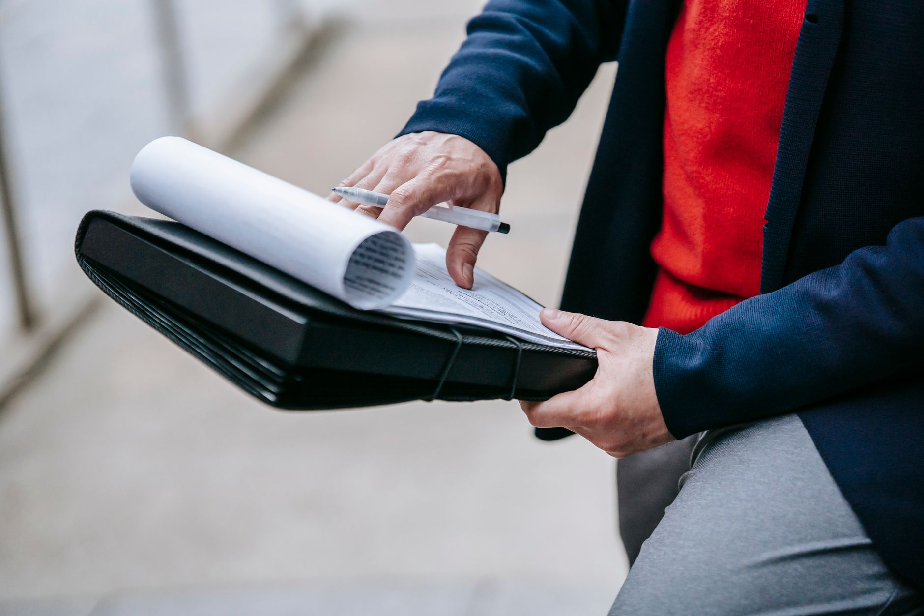 Close-up of a professional person reviewing documents outdoors. Engaged in work with focus on writing materials. — Navigating