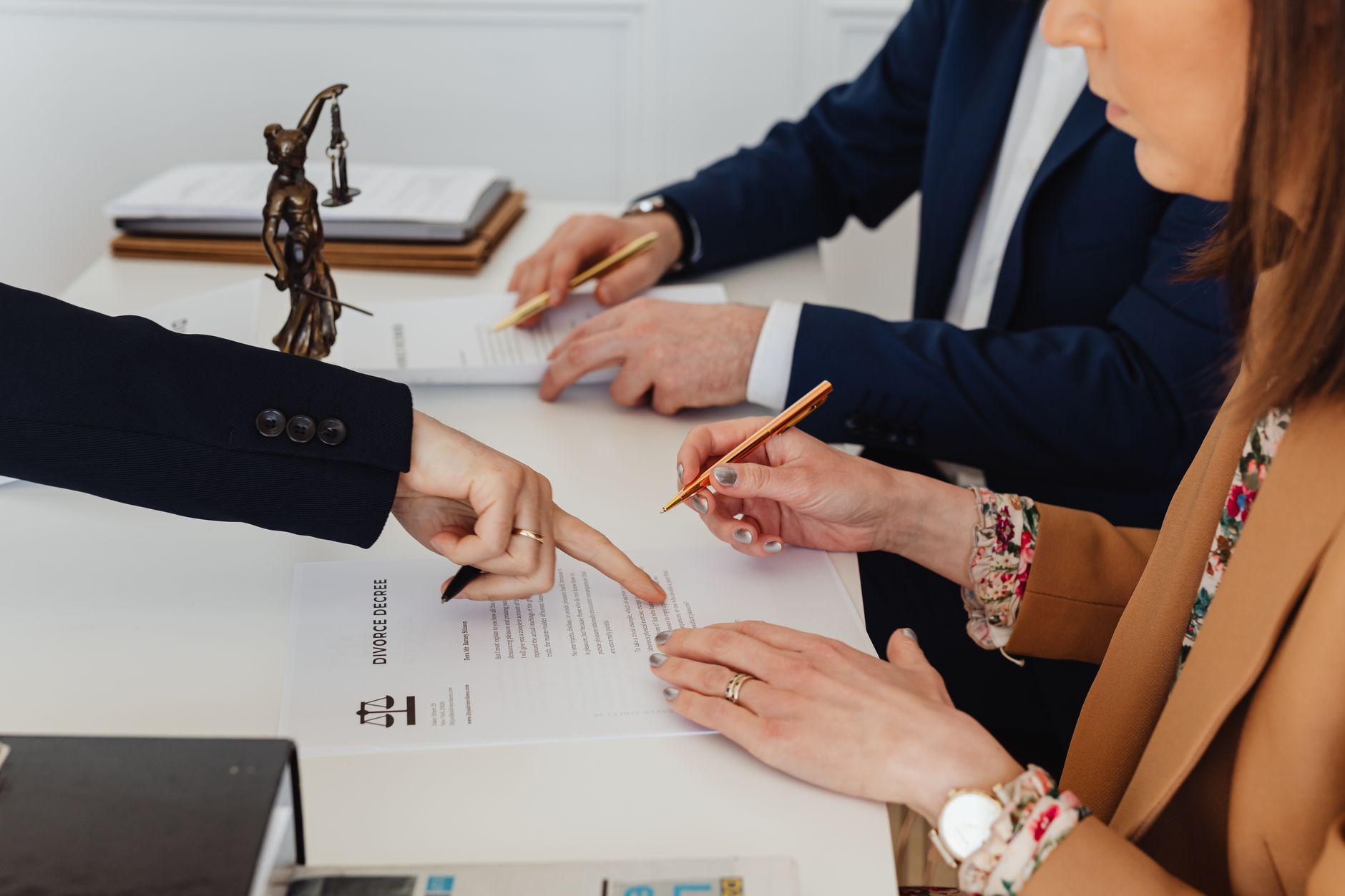 Hands signing a divorce decree, with a justice statue nearby, symbolizing legal proceedings. — Policy Trace Identifies Hidden