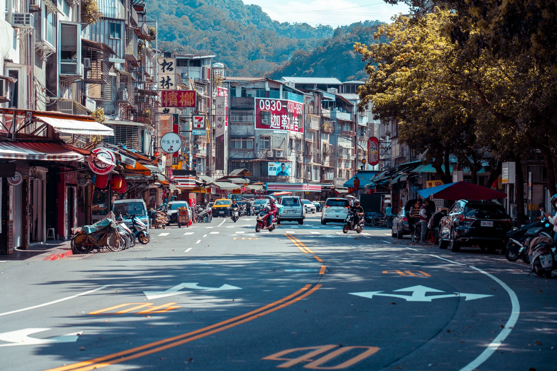 Vibrant urban street scene with shops, vehicles, and mountains in an Asian city. — Sparkling Clean Homes: Our Commitment to H