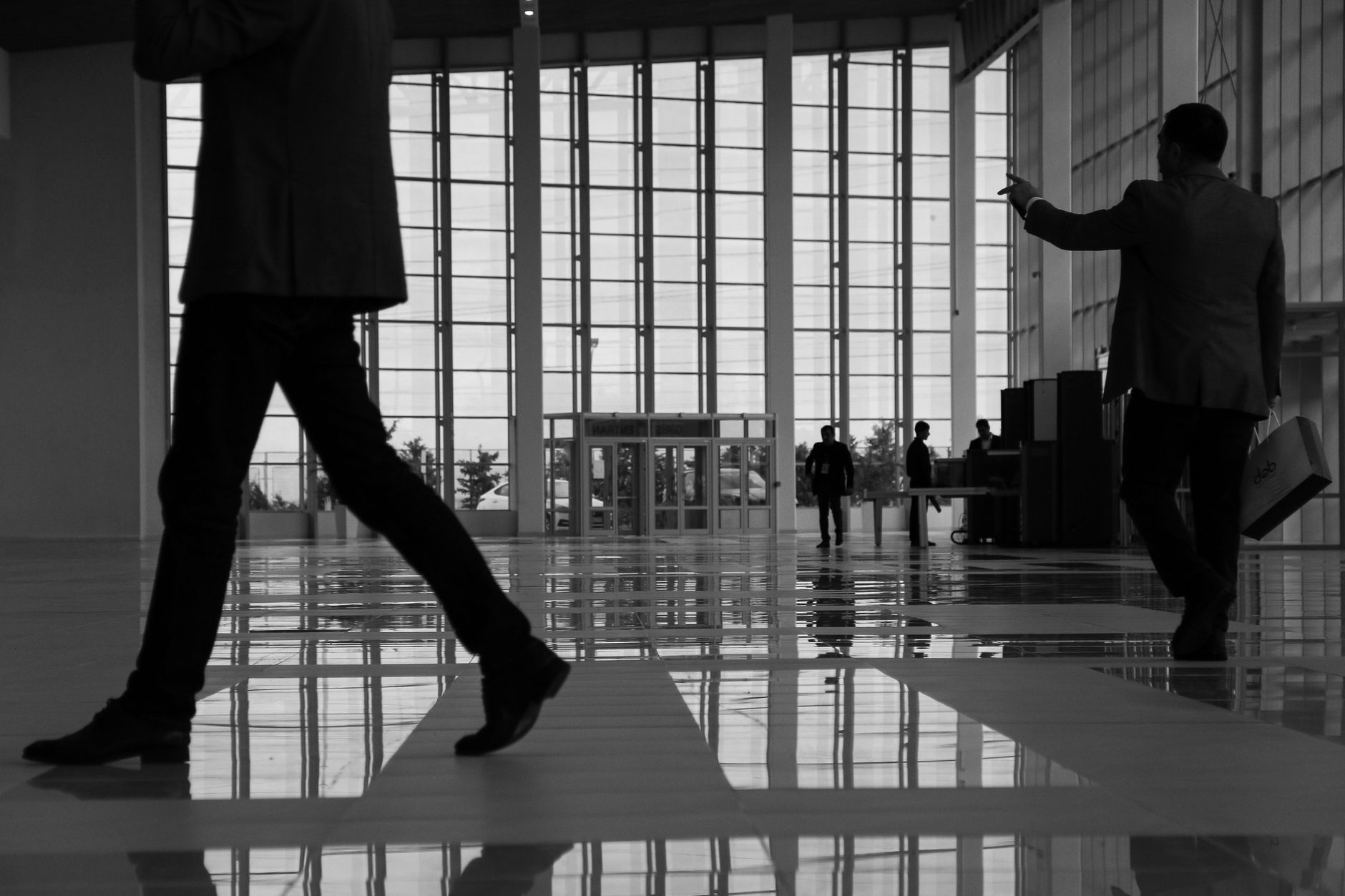 Business professionals walk through a modern, glass-paneled indoor space. — The Athletic Journey of Eric Hollifield: From McD