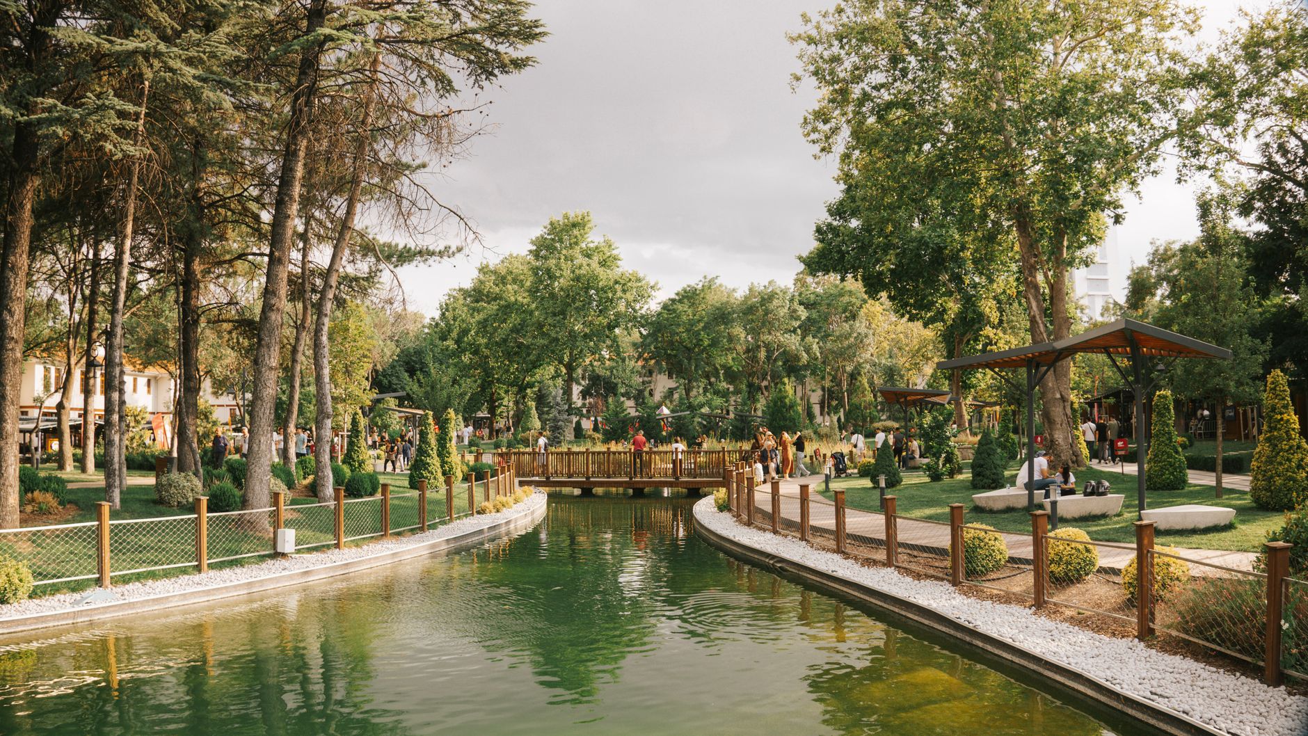 Peaceful park scene featuring a serene pond, a wooden bridge, and lush greenery. — The Impact of Urban Redevelopment on Singa